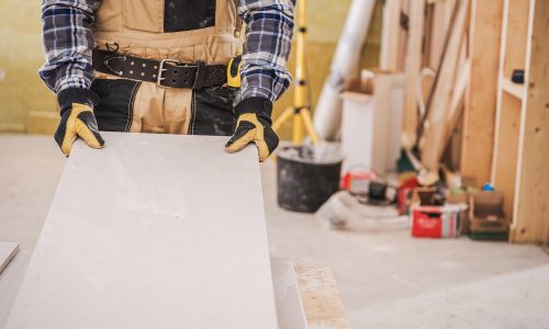 Male Contractor Holding Piece Of Drywall Material.