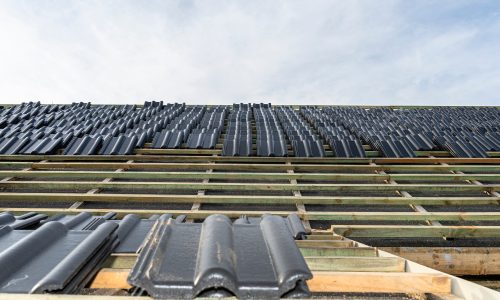 Roof ceramic tile arranged in packets on the roof on roof battens. laying tiles on a boarded roof.